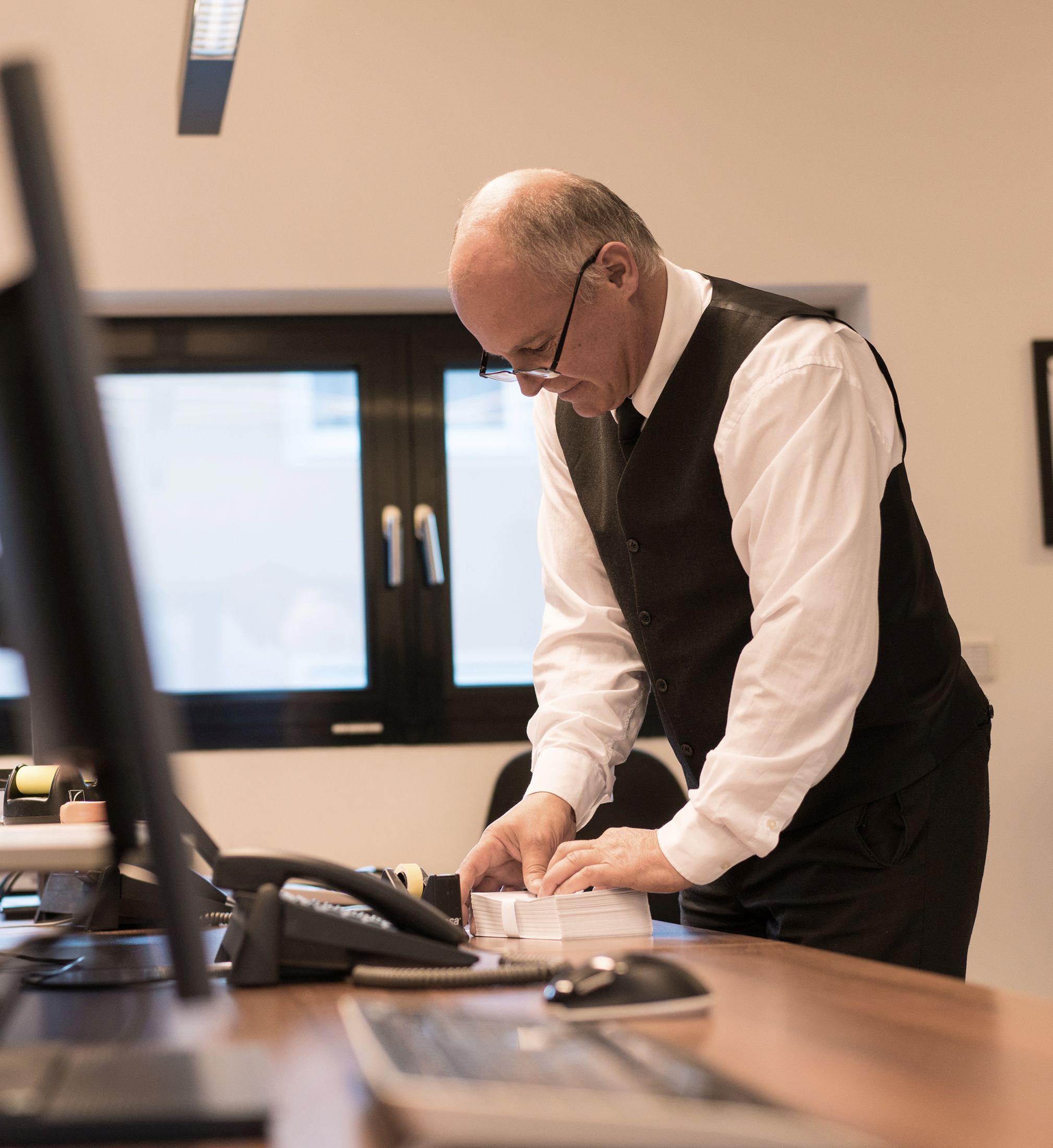 Mitarbeiter im Büro der Bestattung in der Nähe von Innsbruck beim Falten von Sterbebildern